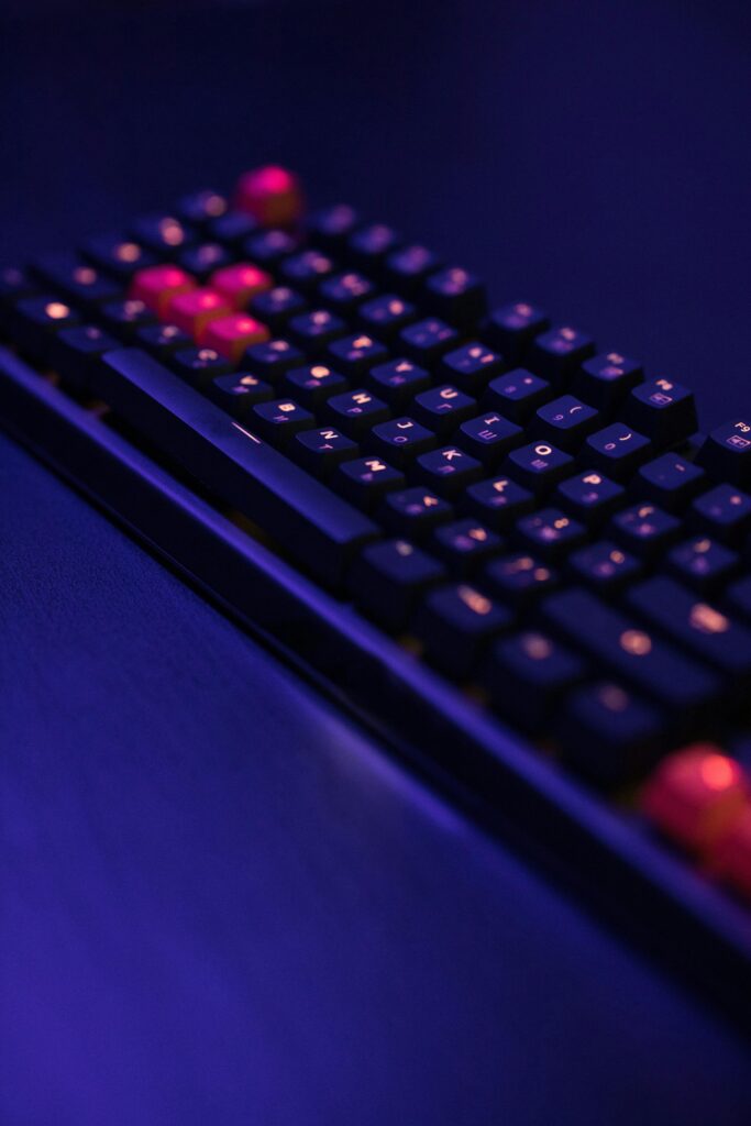 A high-tech gaming keyboard illuminated by vibrant neon blue and red lighting.